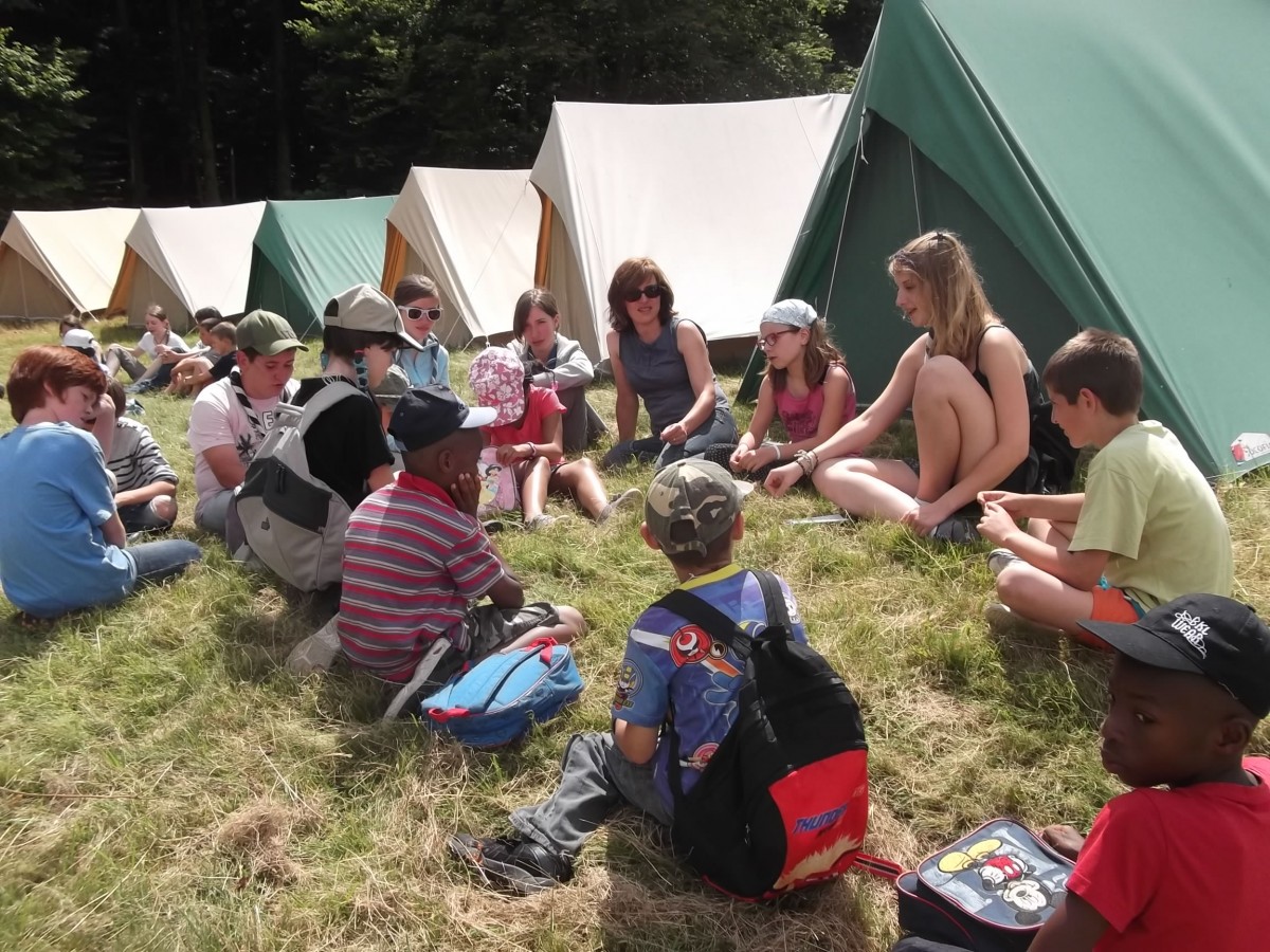 Un groupe de jeunes en cercle devant les tentes du camp